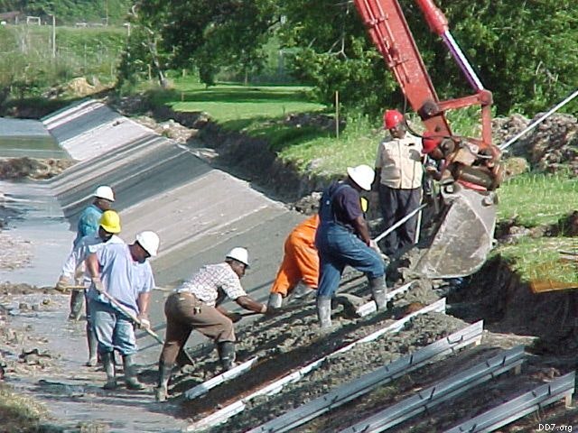 Construction workers with an excavator building or repairing a concrete canal.