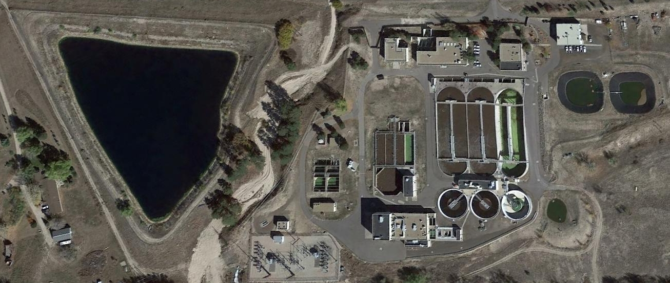 Aerial view of a water treatment plant next to a large pond.