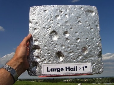 A person holds a foil-covered board with visible dents, labeled "Large Hail ≥ 1 inch."