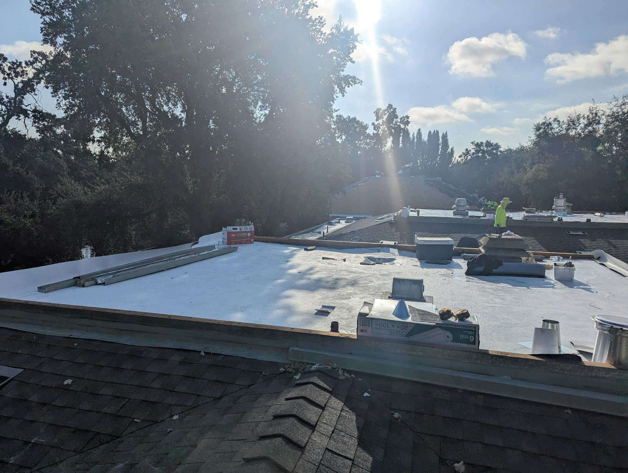 A flat roof with construction materials and a person working under a sunny sky.