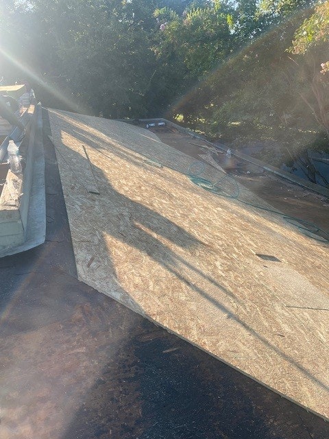 OSB boards being installed on a rooftop with sunlight casting shadows.