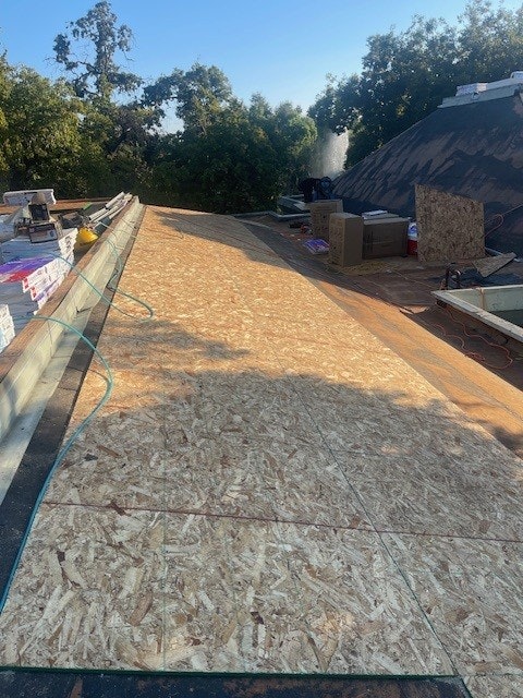 Wooden decking and construction materials on a flat roof surrounded by trees.