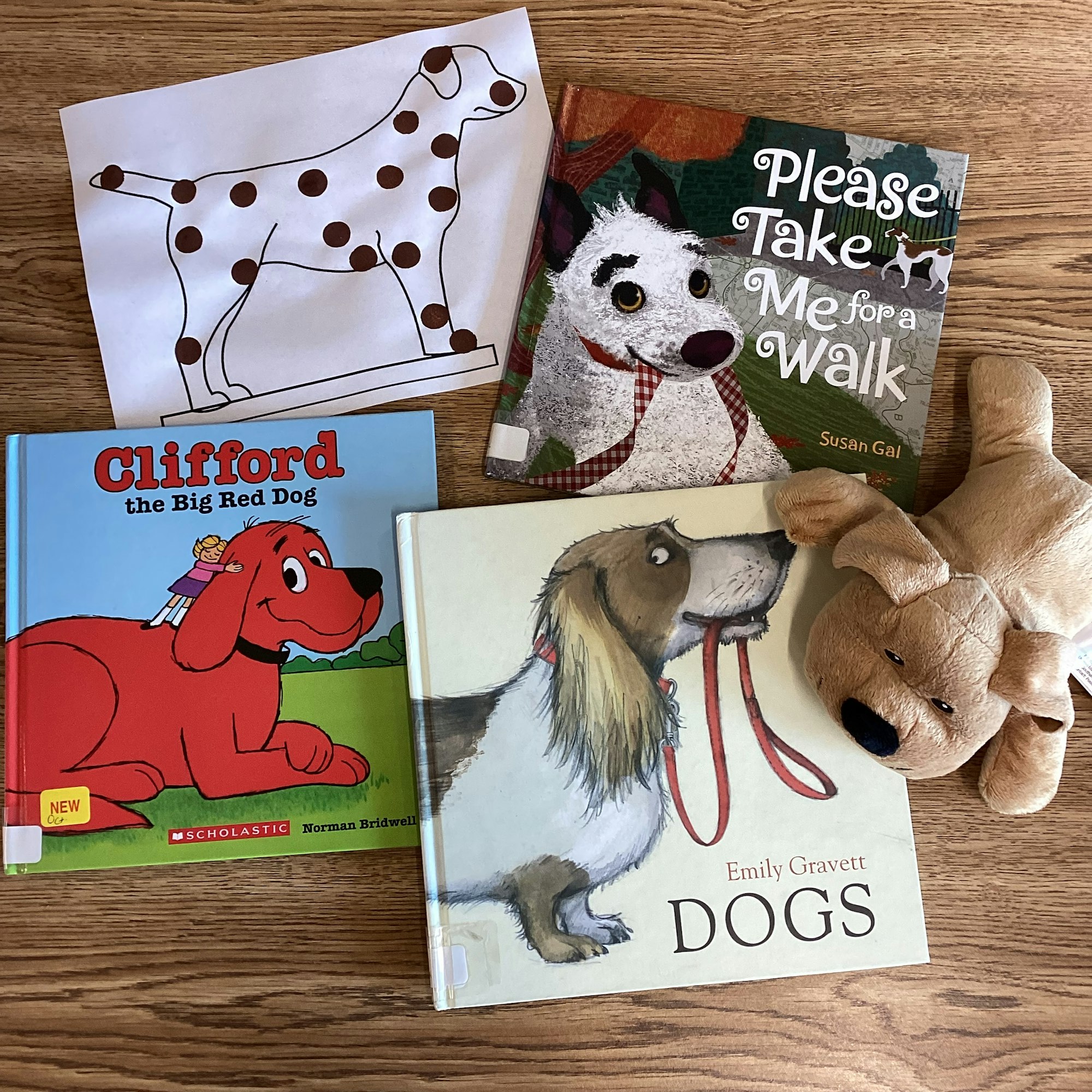 Three children's books about dogs, a stuffed toy dog, and a drawing of a spotted dog.