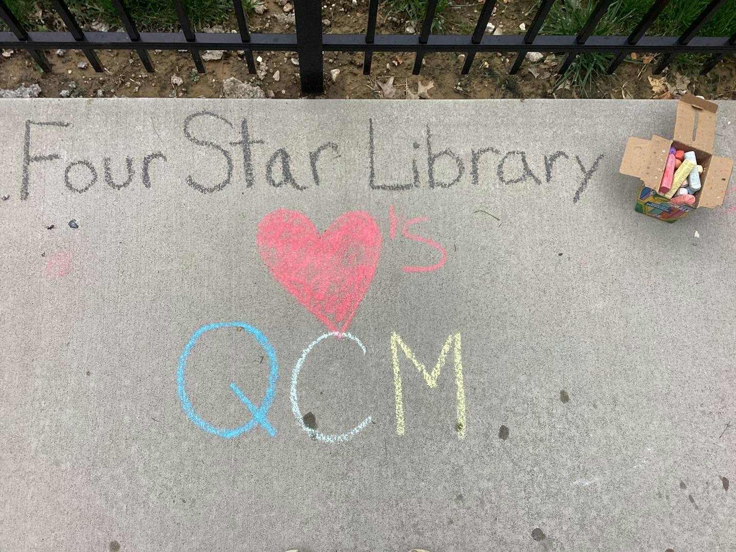 Sidewalk chalk art reads "Four Star Library ♥'s QCM" with a box of chalk nearby.