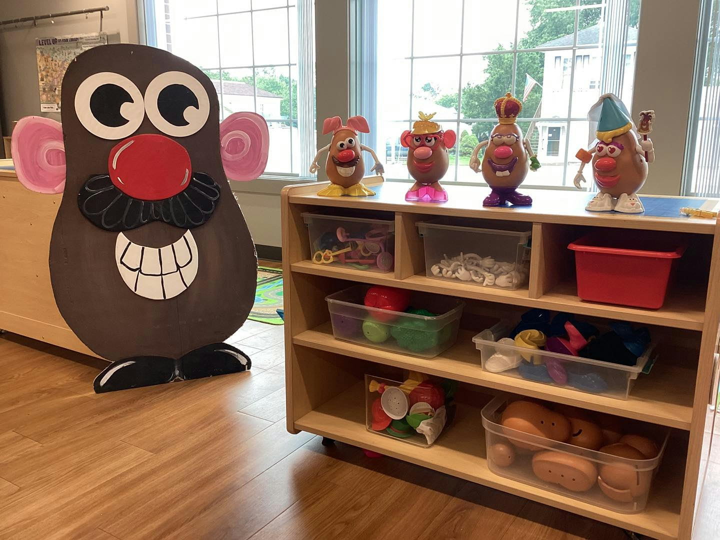 Toy shelf with Mr. Potato Head figures and accessories, and a large Mr. Potato Head cutout.