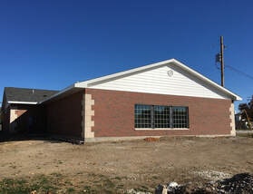 A single-story brick building with large windows and a gabled roof on a clear day.