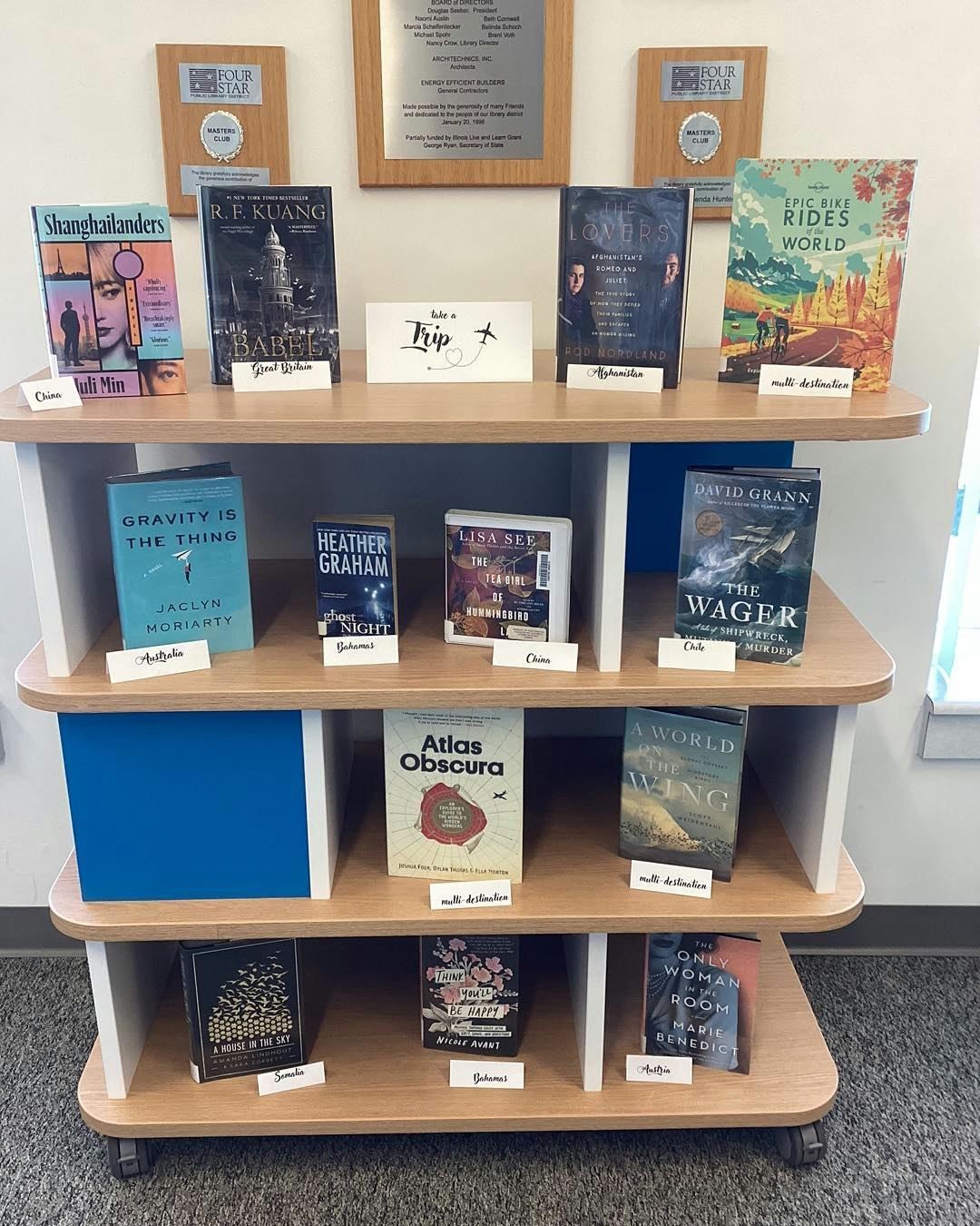 Books displayed on a shelf with travel-themed labels like China, Bahamas, and multi-destination.