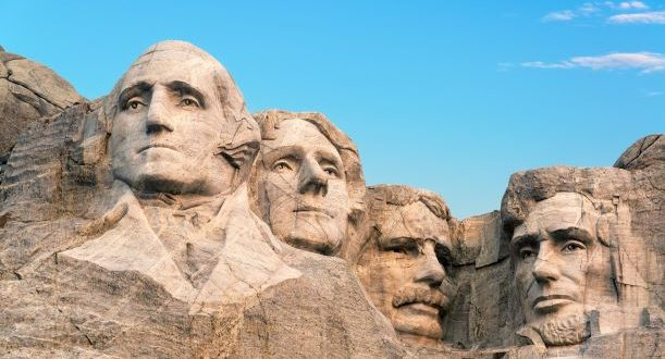The image depicts Mount Rushmore, featuring the carved faces of four U.S. presidents: Washington, Jefferson, Roosevelt, and Lincoln.