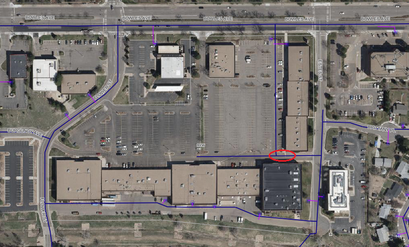 The image is an aerial view of a commercial area showing buildings, parking lots, and streets, marked with paths and labels.