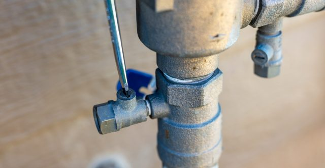 The image shows a close-up of a metal valve and piping, possibly part of a plumbing or irrigation system.
