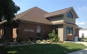 A brick building with a sign that reads "Groff Memorial Library & Museum," surrounded by grass and shrubs.