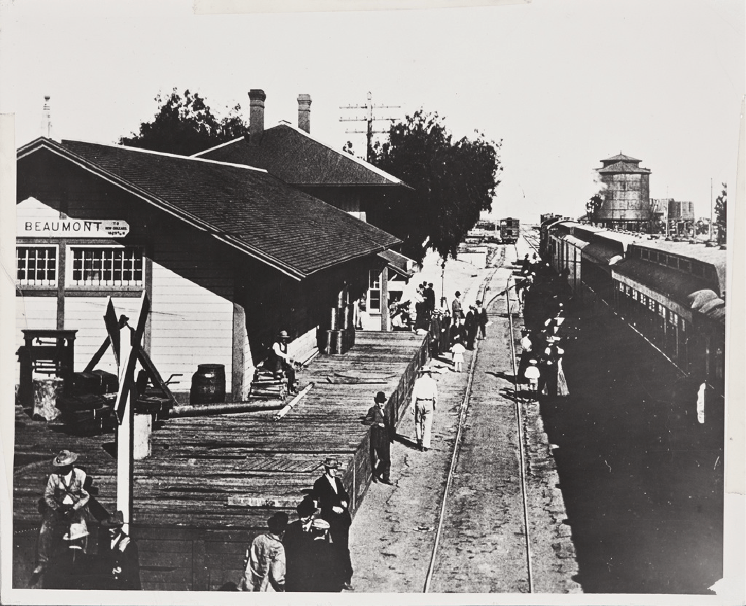 Vintage train station with people and a train, labeled "BEAUMONT."