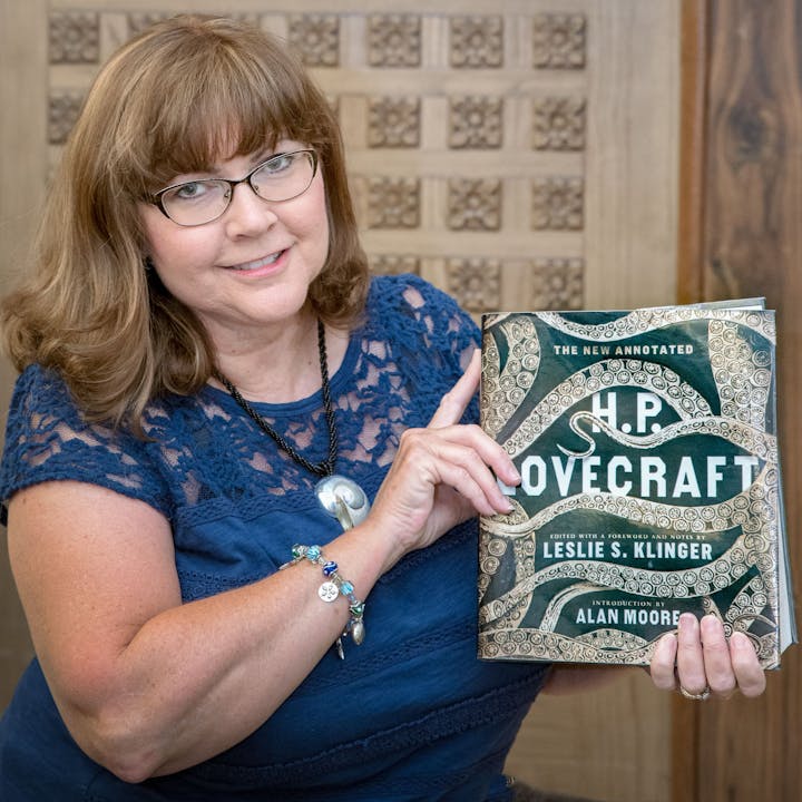 A person holding "The New Annotated H.P. Lovecraft" book, smiling at the camera.