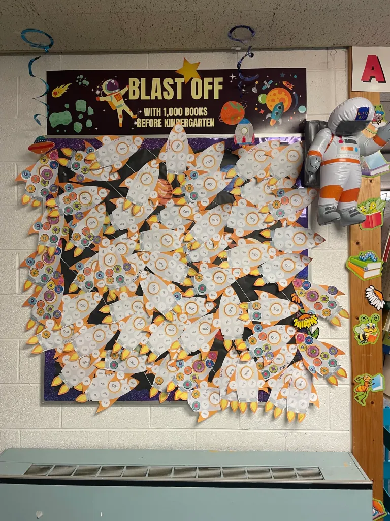 Classroom bulletin board with a "Blast Off" theme, featuring rocket crafts tracking books read before kindergarten.