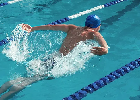 A swimmer in a blue cap doing the freestyle stroke in a pool.