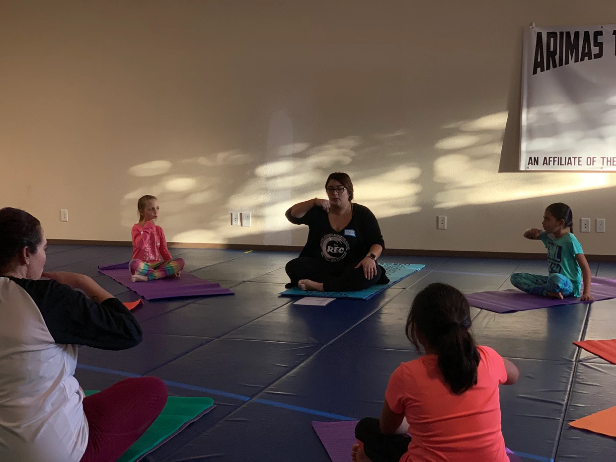 A yoga class with an instructor and participants on mats in a dimly lit room.