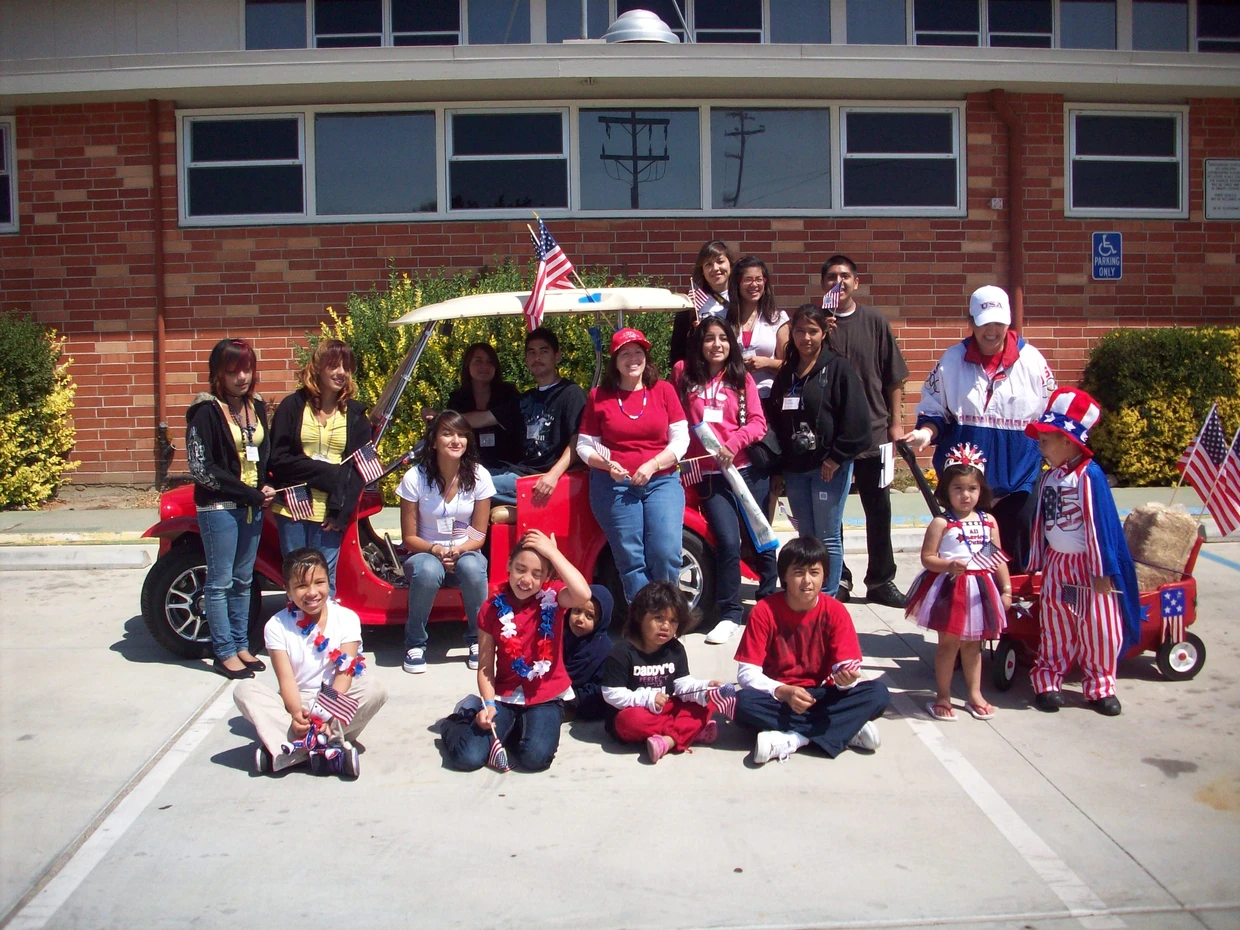 Group of people with American flags, showing patriotic spirit, possibly at a parade or celebration.