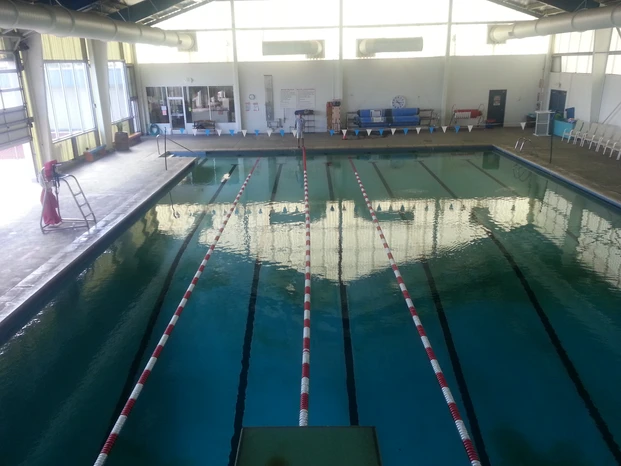 Indoor swimming pool with lane dividers, starting blocks, and seating area.