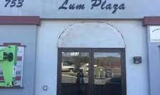 Storefront with the sign "Lum Plaza," glass door, and a green flyer on the left.