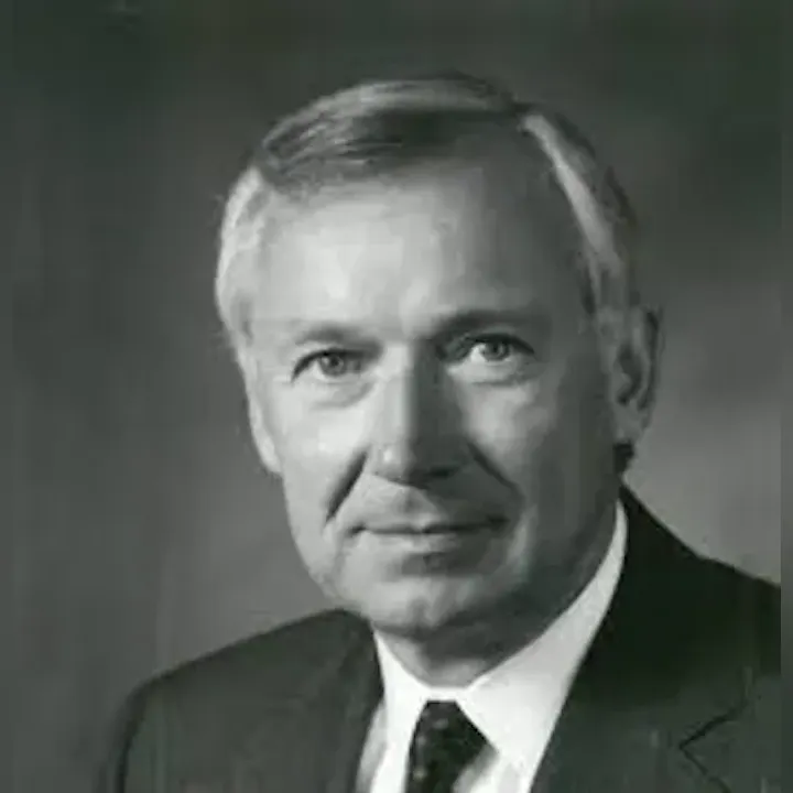 Black and white portrait of a man in a suit and tie, looking at the camera.