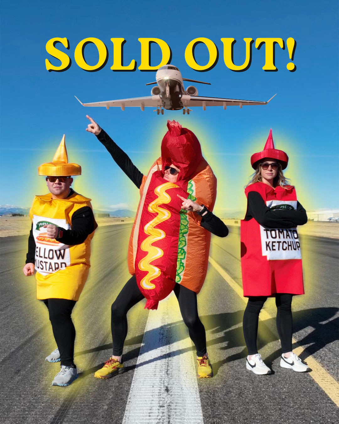 Three people in food costumes (hot dog, mustard, ketchup) pose on a runway with a plane above, captioned "SOLD OUT!"