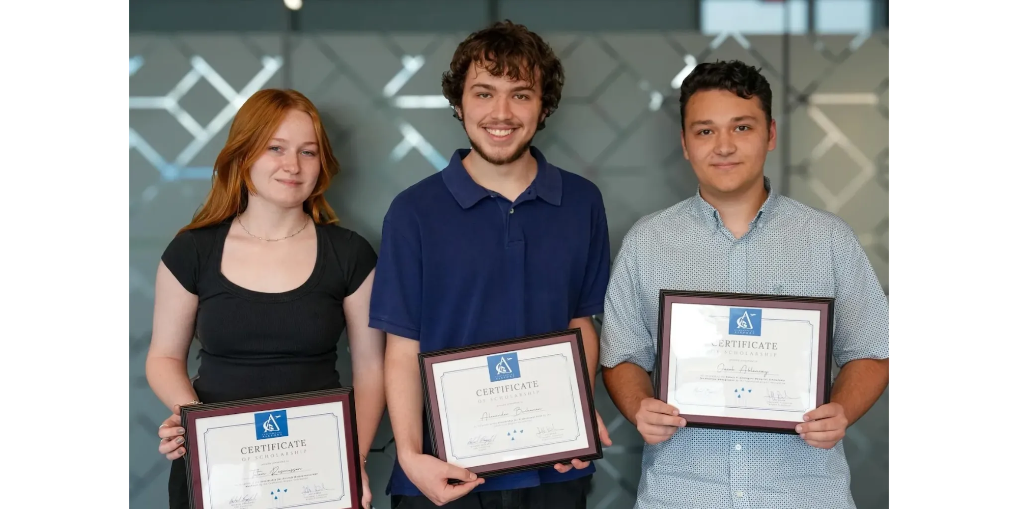 Three people holding certificates and smiling at the camera.