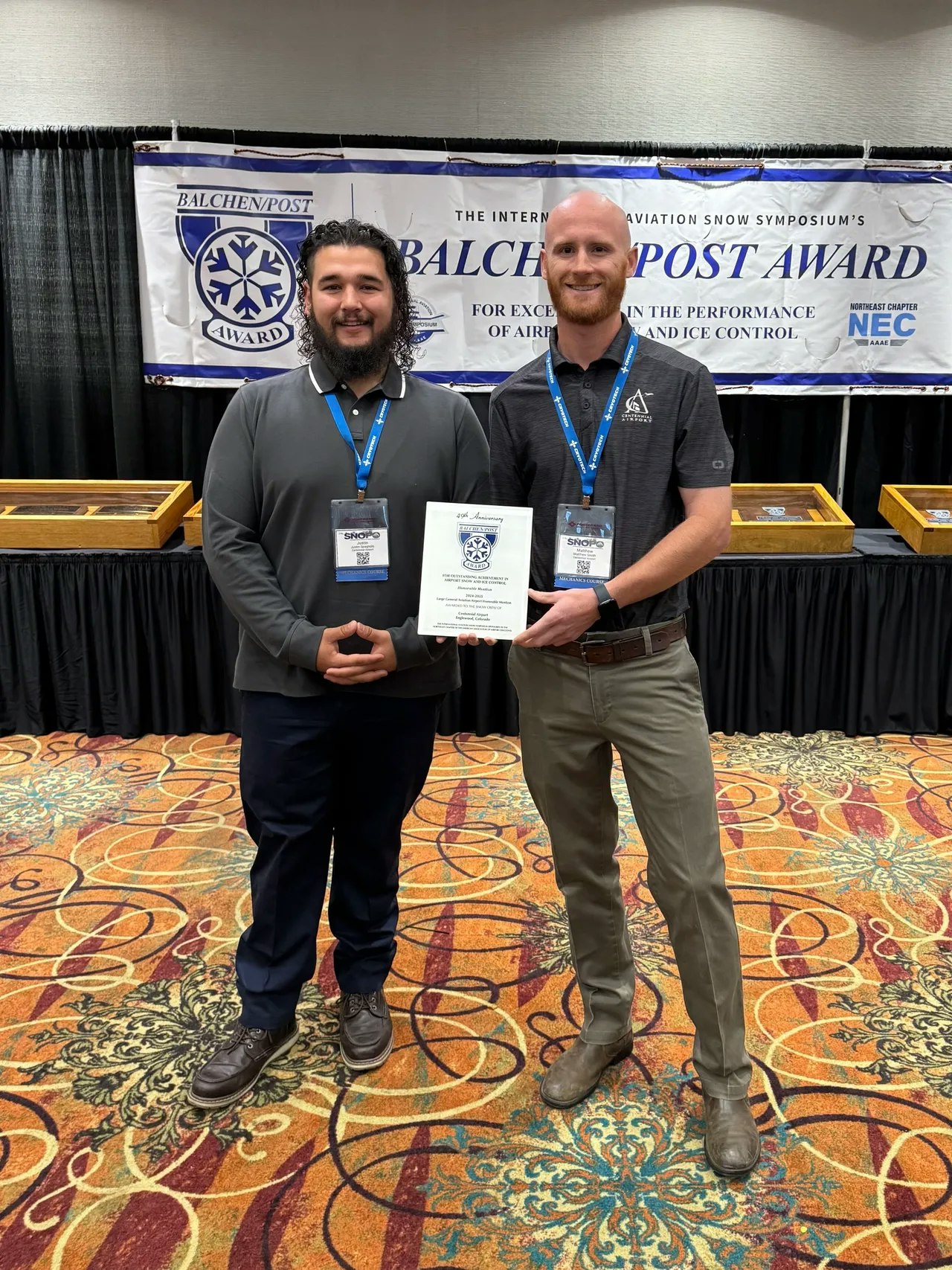 Two people standing with an award at the Balchen/Post Award ceremony, related to airport snow and ice control.