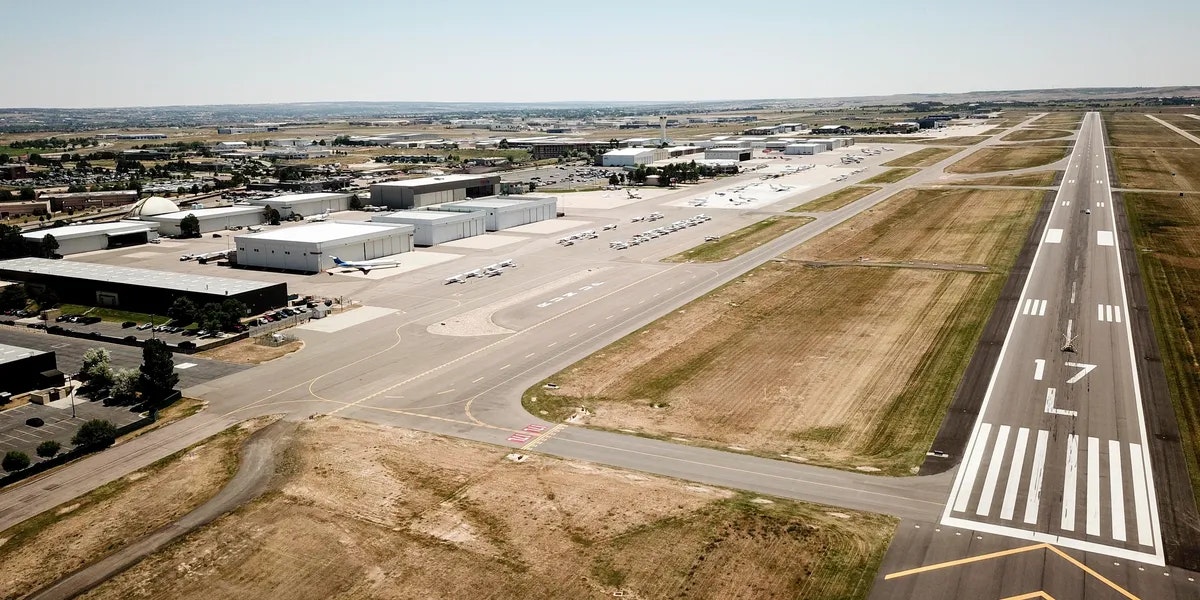 Airport runway with hangars and small airplanes parked nearby.