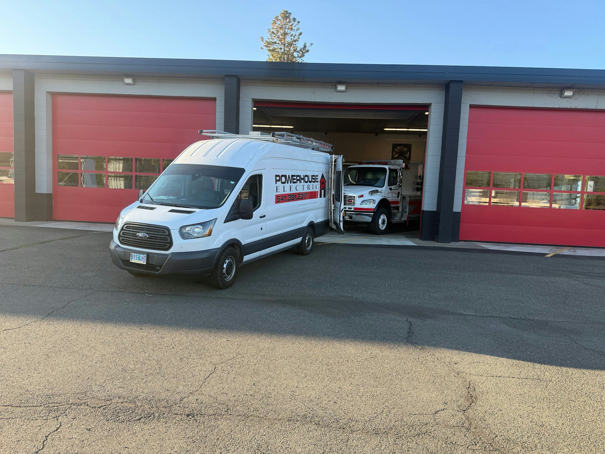 A white van labeled "Powerhouse Electric" is parked in front of a building with red garage doors.