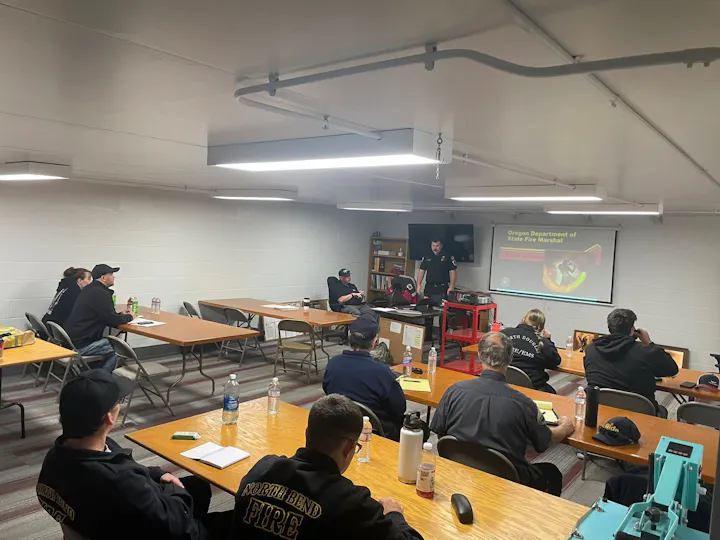 A group of people in a classroom setting attending a fire safety training session led by a speaker.