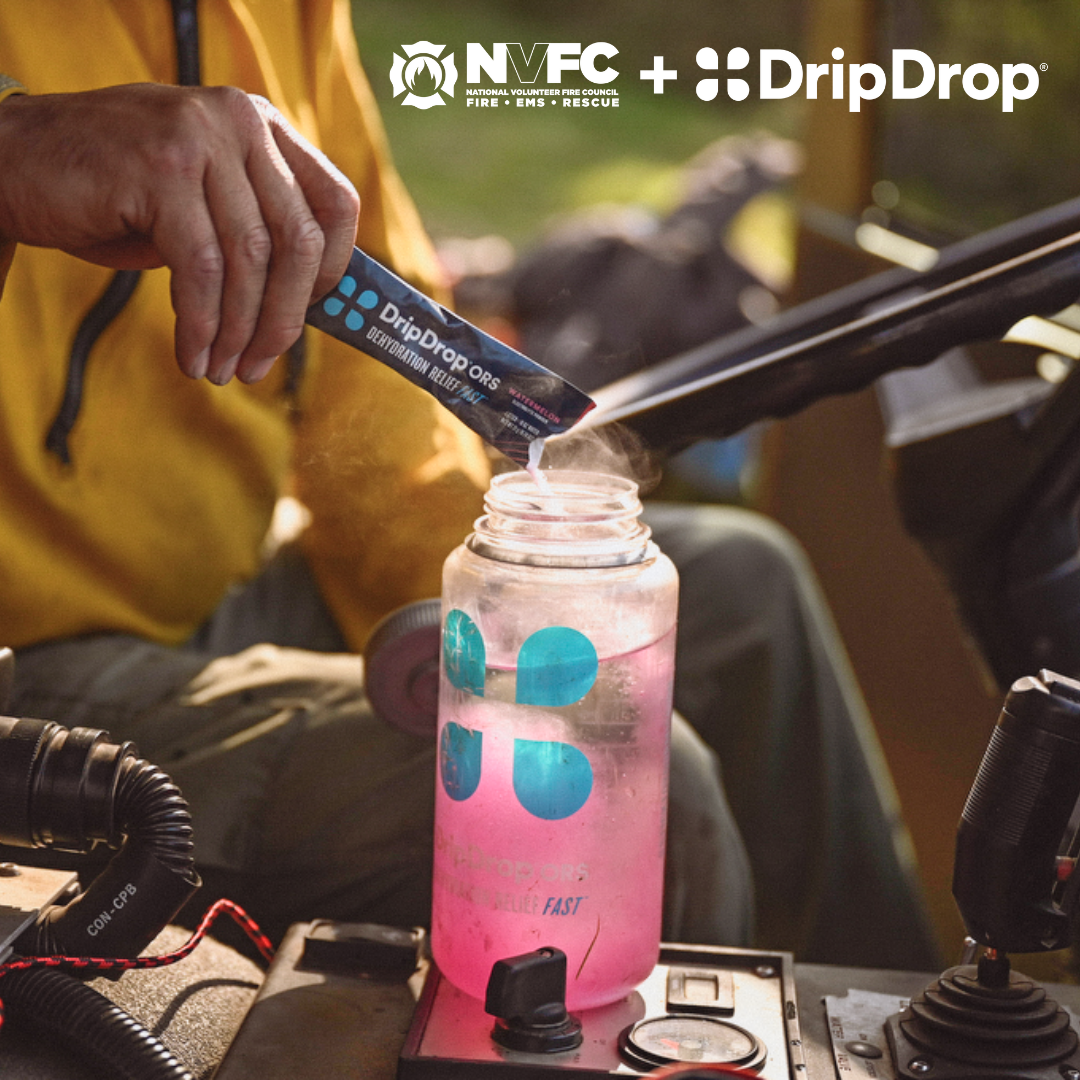 A person adds DripDrop electrolyte powder to a clear sports bottle, mixing it with water, in an outdoor setting.