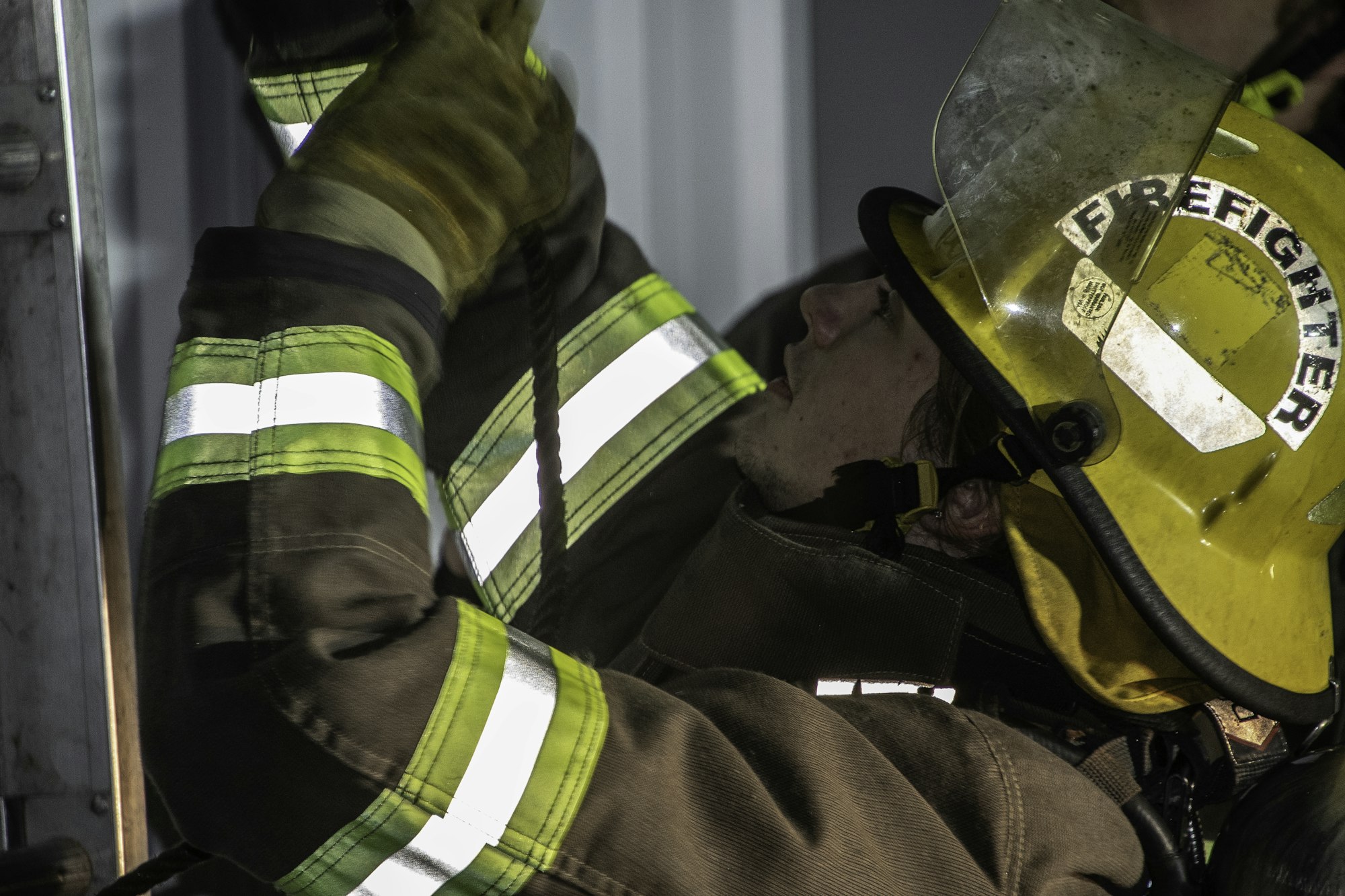 A firefighter in gear is working with ropes or equipment, showcasing dedication and readiness for emergency response.