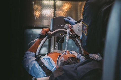 Emergency medical technicians use a device to assist a patient, suggesting an urgent medical situation.
