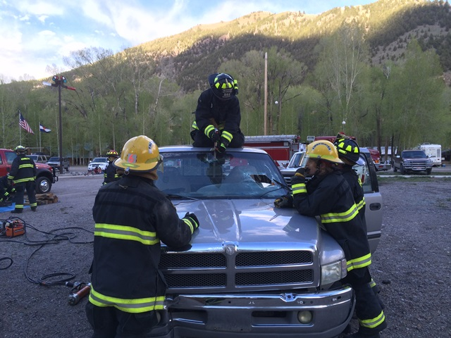 Firefighters training with equipment on a truck.