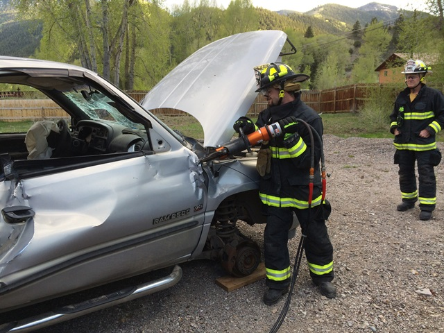 Firefighters use equipment on a damaged car during a rescue training or operation.
