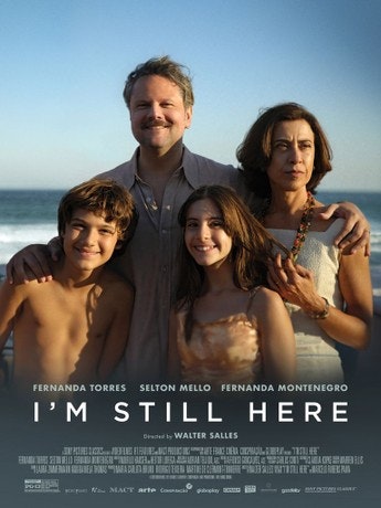 A family of four posing together in front of a beach, with the text "I'M STILL HERE" and names Fernanda Torres, Selton Mello, Fernanda Montenegro.