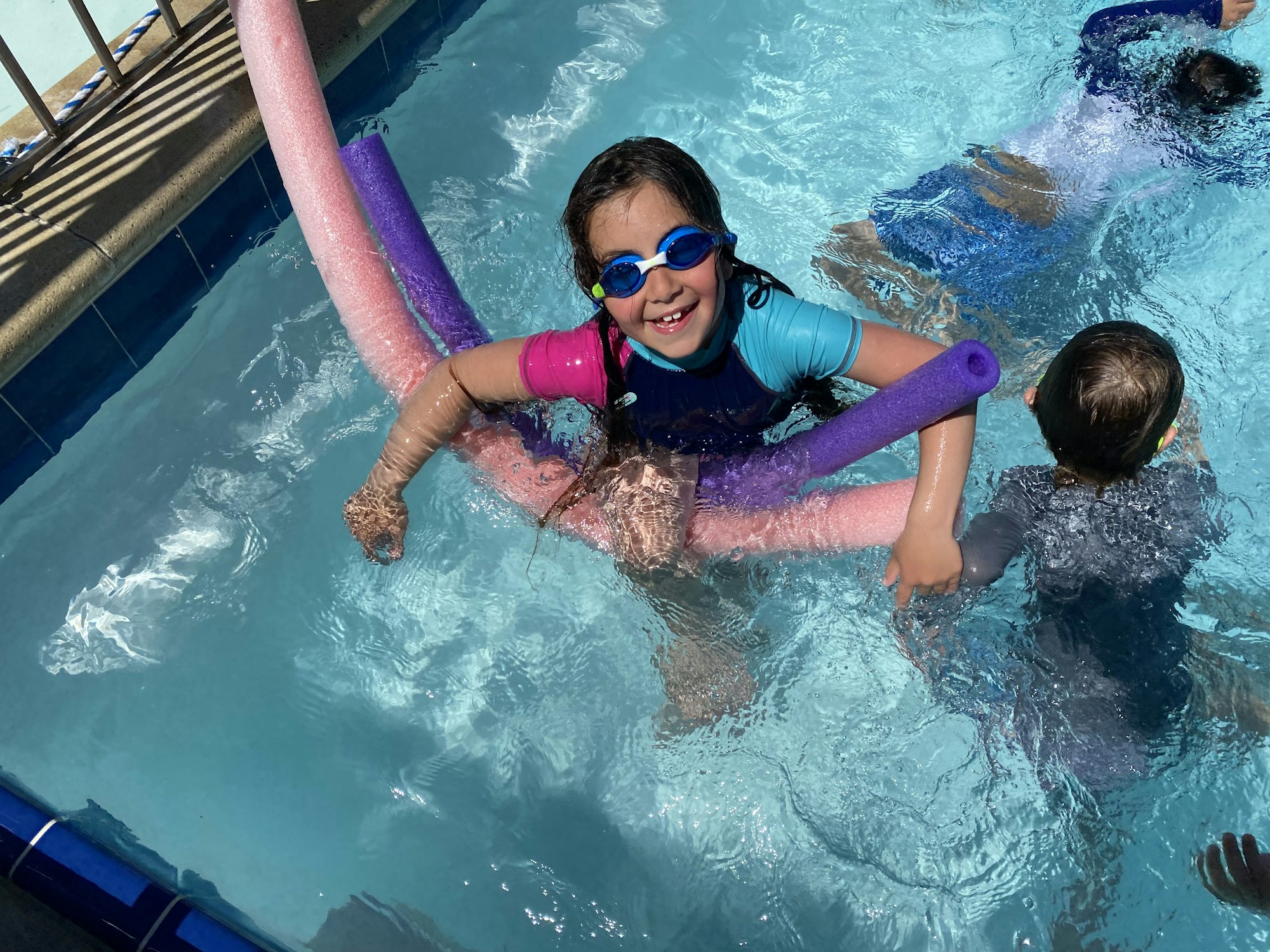 May contain: leisure activities, person, sport, swimming, water, water sports, pool, summer, swimming pool, clothing, lifejacket, vest, face, head, photography, portrait, accessories, and sunglasses