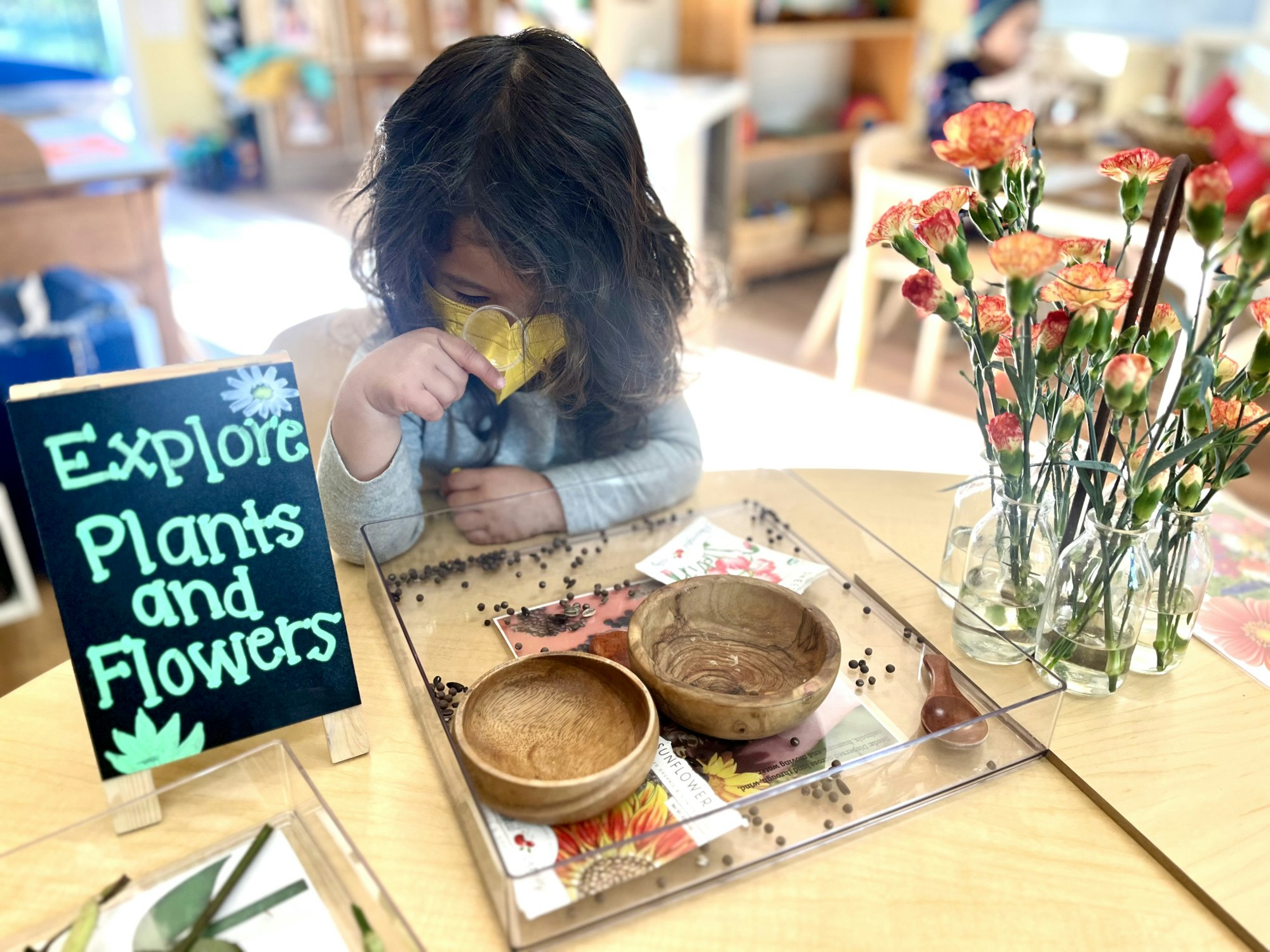 May contain: flower, flower arrangement, plant, flower bouquet, child, female, girl, person, face, head, photography, portrait, indoors, interior design, dining table, furniture, table, and pottery