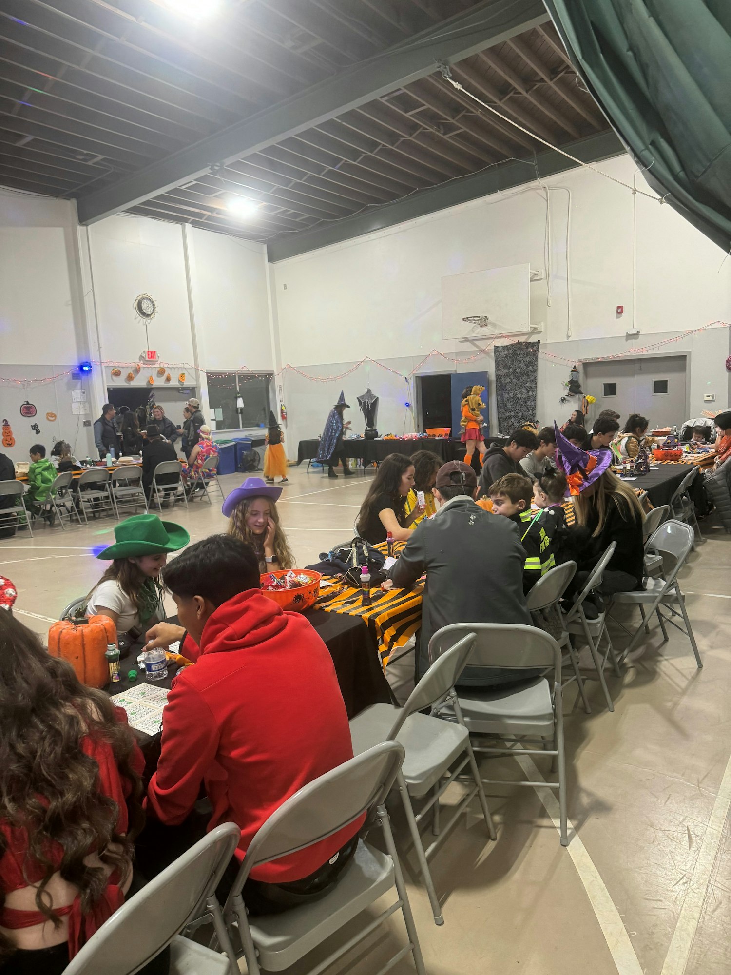 A Halloween-themed event with people in costumes, sitting at tables with festive decorations.