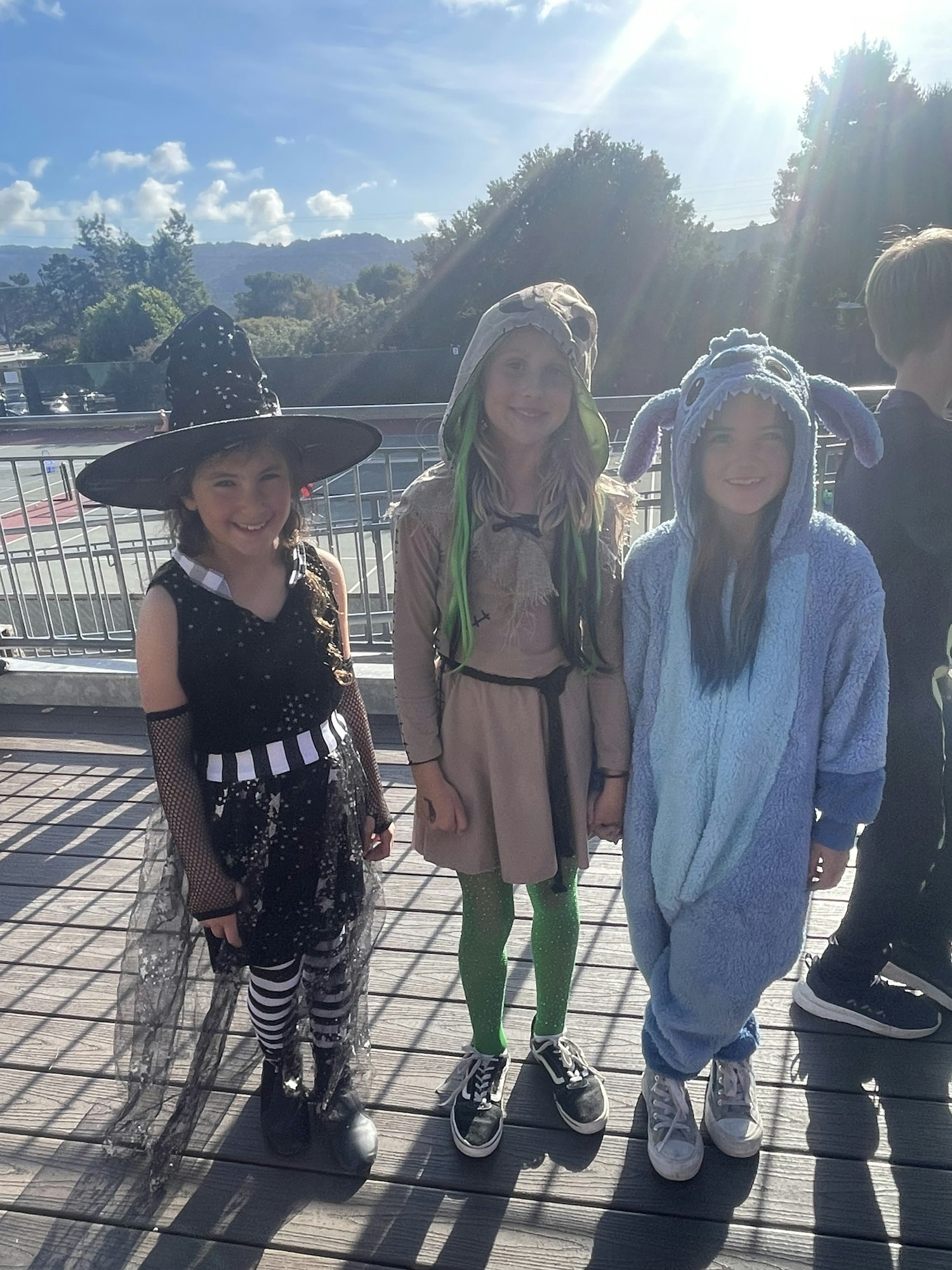 Three people in costumes smiling outdoors (image is rotated 90 degrees).