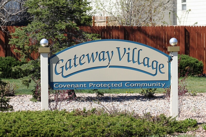 A sign reads "Gateway Village Covenant Protected Community" with a landscaped backdrop.