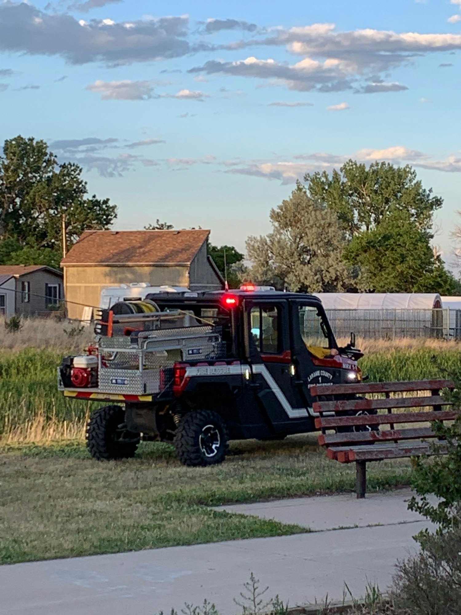An off-road vehicle with emergency equipment parked near a house and trees.