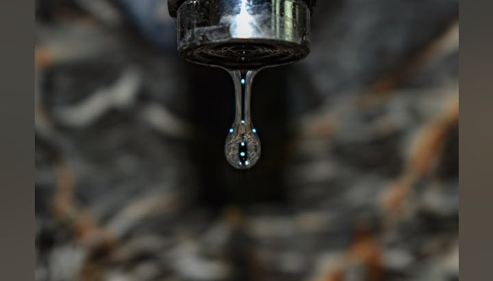 A water droplet about to fall from a faucet.