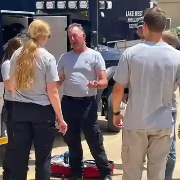 A group of people in uniform next to an ambulance, possibly engaged in discussion or training.