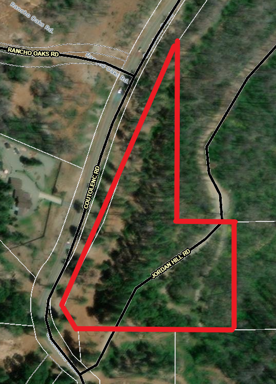 A satellite map view featuring roads with labels and an outlined area in red.