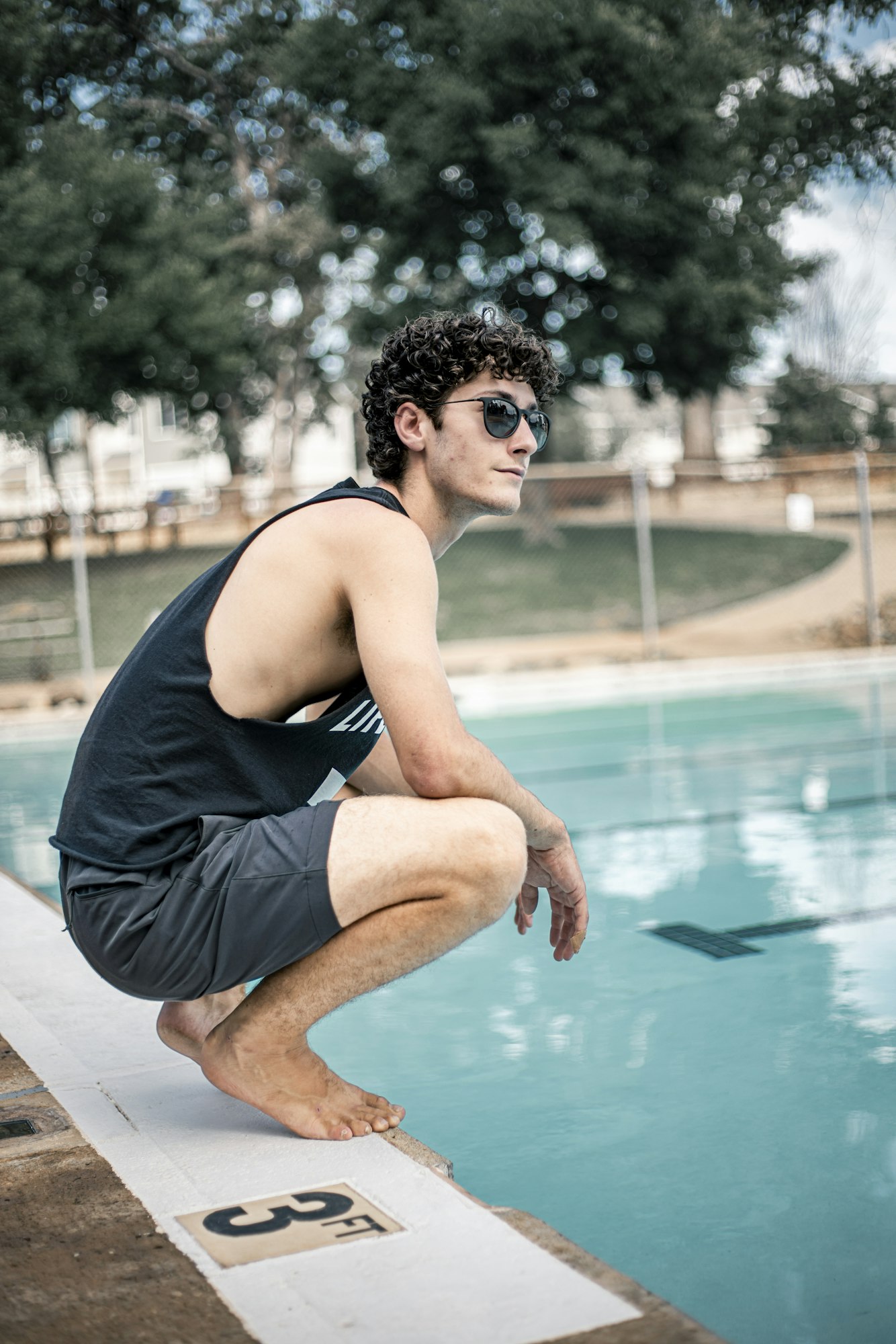 A person in sunglasses squats by a pool, marked "3 FT" with trees in the background.