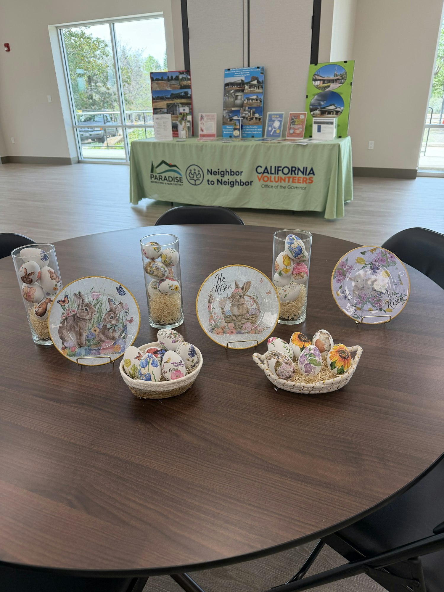 The image shows decorative plates and baskets with floral designs and eggs on a table, along with a promotional display area.