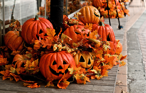 Jack-o'-lanterns and autumn leaves arranged on a wooden surface, creating a festive fall display.