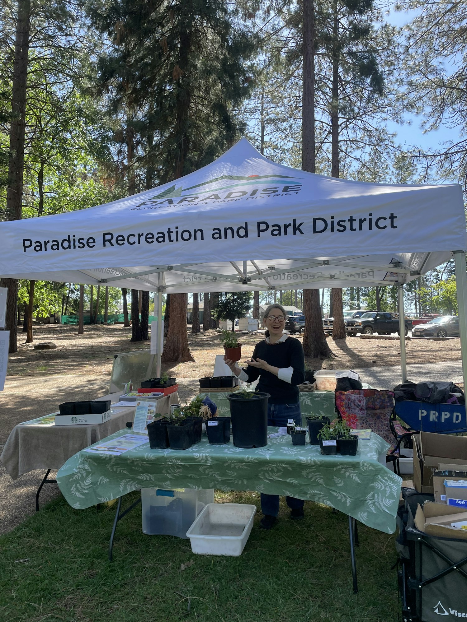 A booth under a tent from "Paradise Recreation and Park District," with a person engaging at a table with plants and materials.