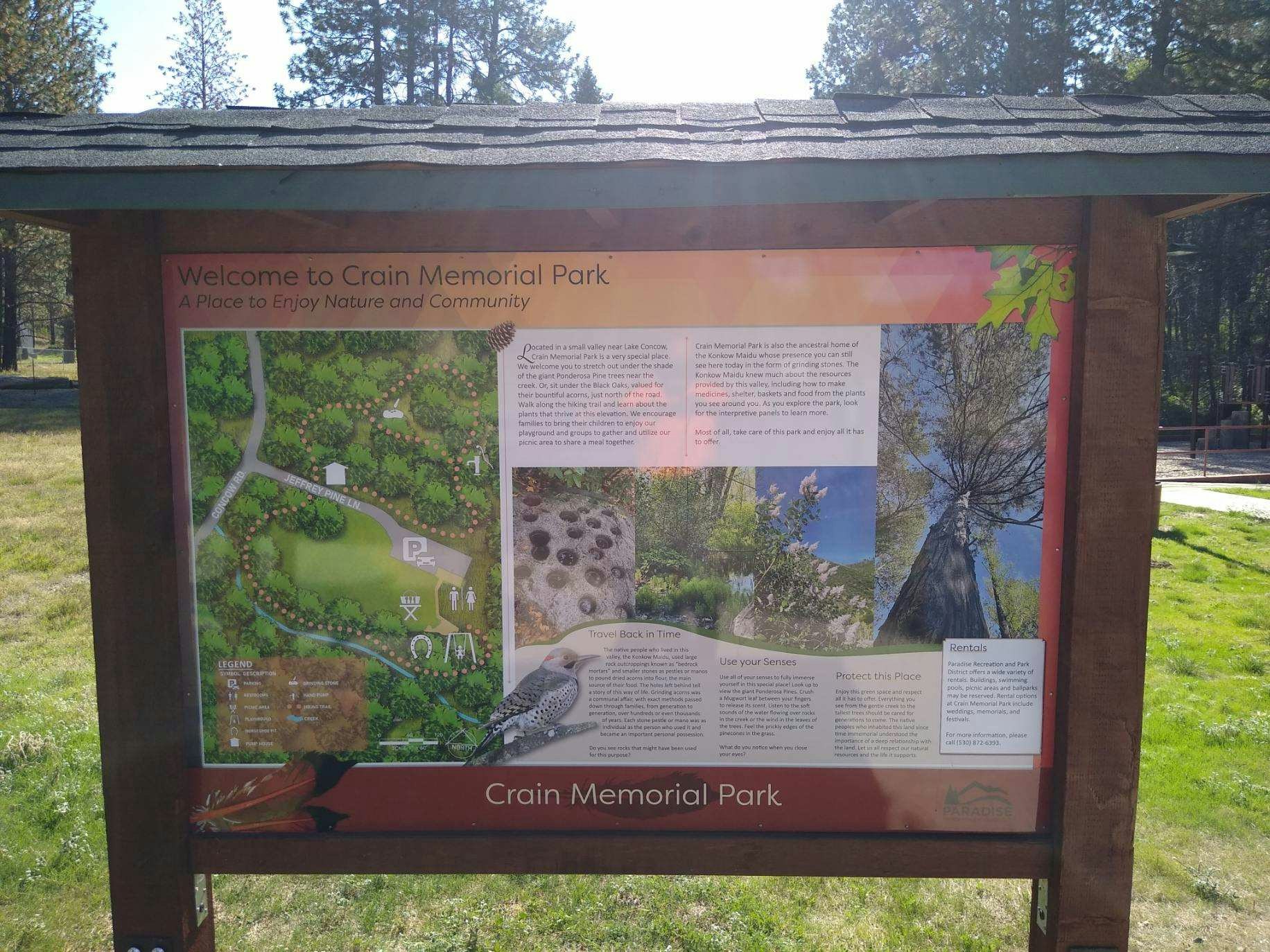 Educational kiosk and welcome sign at Crain Park that includes a bird, grinding stones, trees, vegetation and a park map